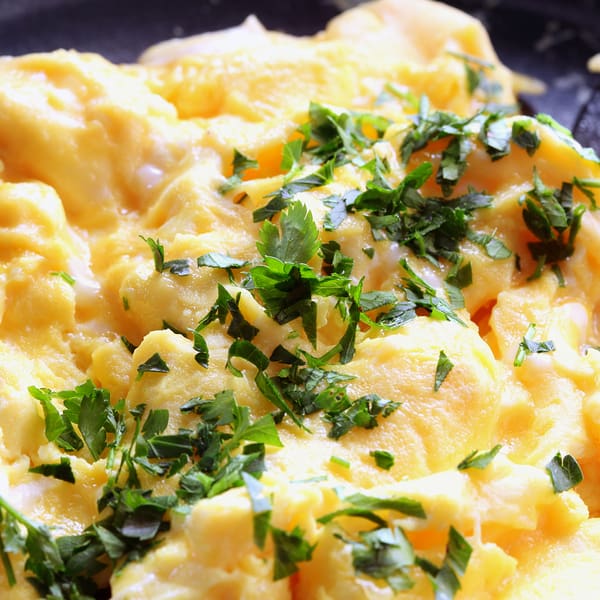 Scrambled eggs cooking in a fry pan, garnished with parsley. Argosy