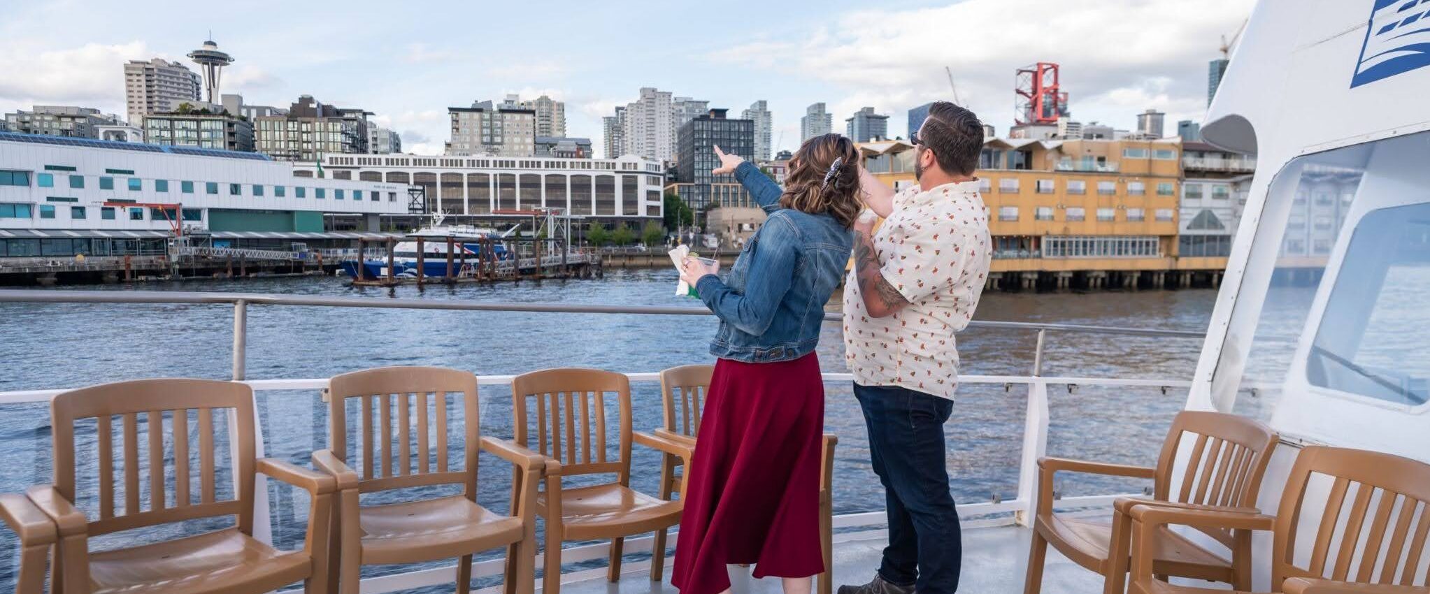 Two people standing on an Argosy Cruise looking towards Seattle