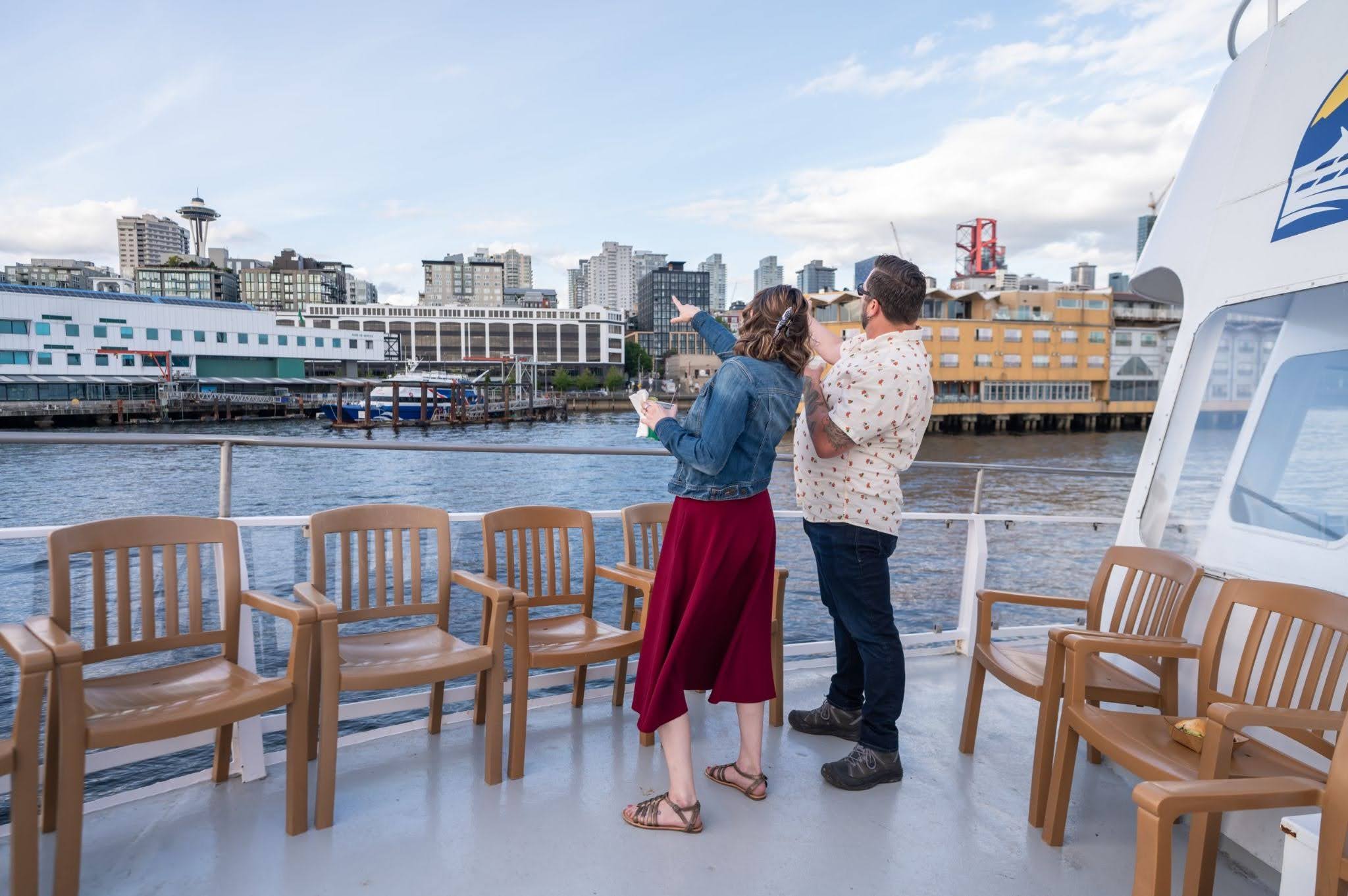 Two people standing on an Argosy Cruise looking towards Seattle